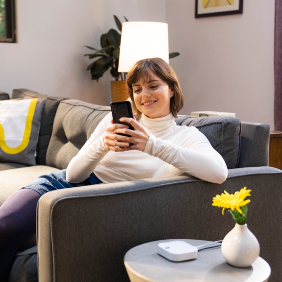 A smiling woman relaxed on the sofa, looking at her smartphone